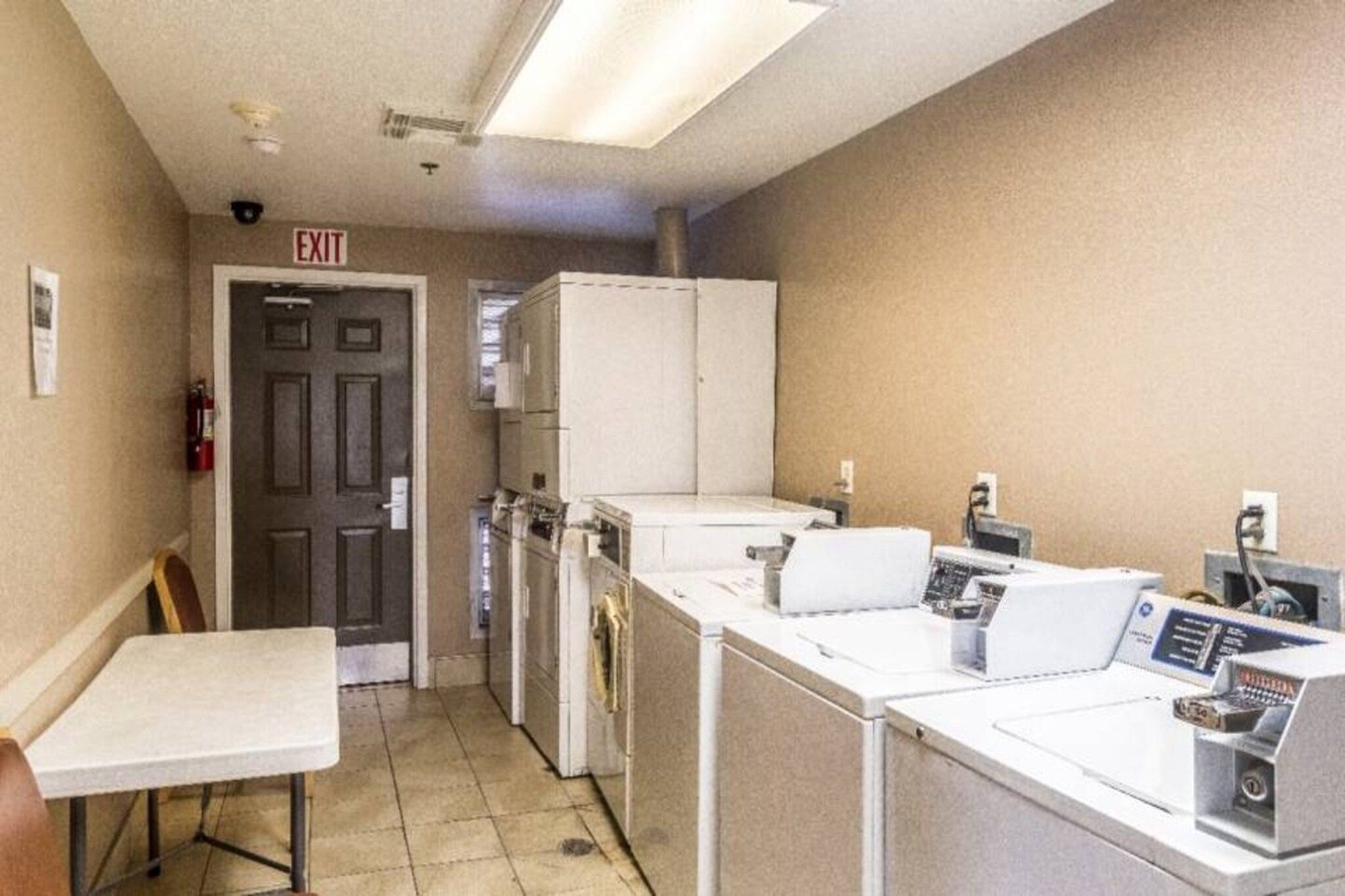 A laundry room with a table, chairs, and multiple washing machines.