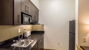 A compact kitchen with a microwave, toaster, sink, and a refrigerator.