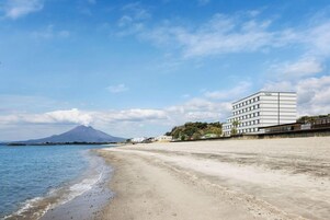 A beach with a building and a mountain in the background.