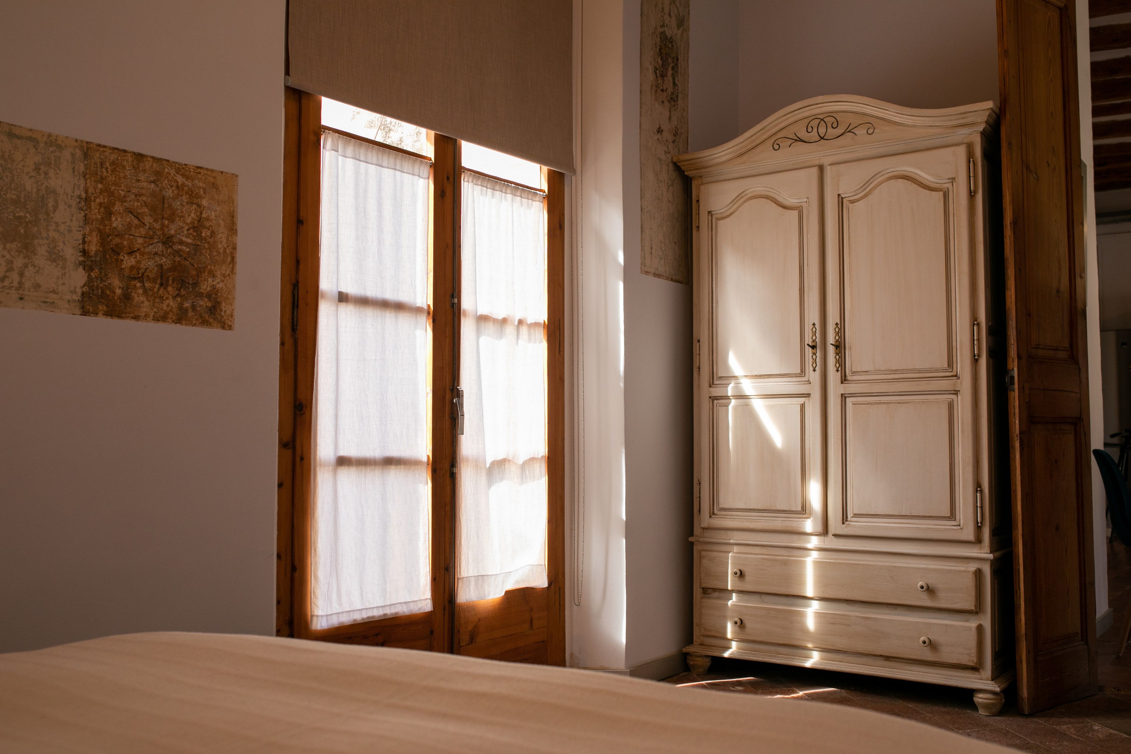Quarto com cama, guarda-roupa e janela com cortinas.
