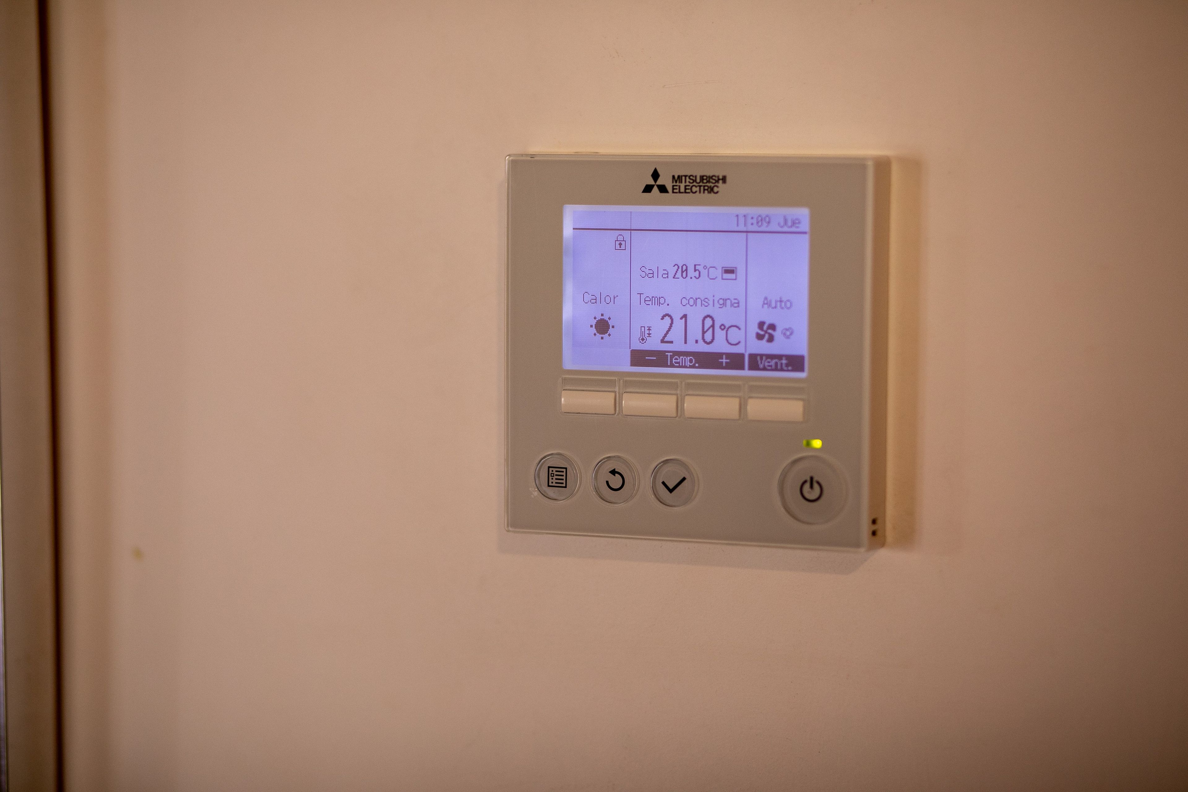En Mitsubishi Electric termostat monteret på en væg, digitalt display viser indstilling for rumtemperatur.