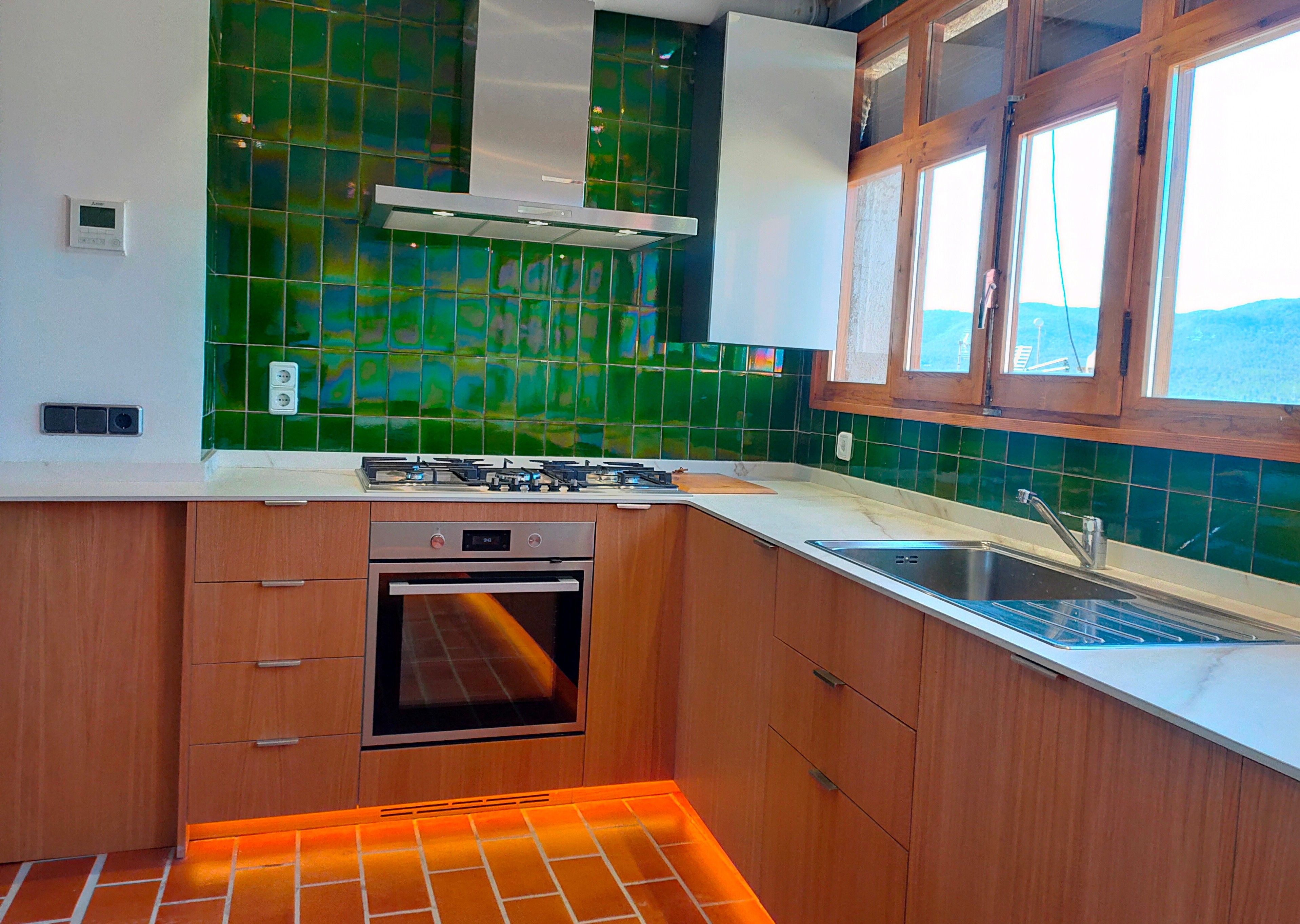 Una cucina con piano cottura a gas, forno e una finestra vista.