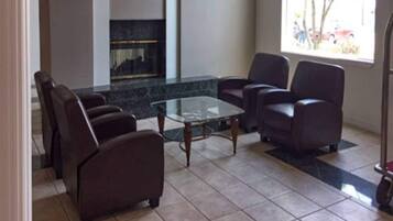 A living room with a glass coffee table, leather sofas, and a tiled floor.