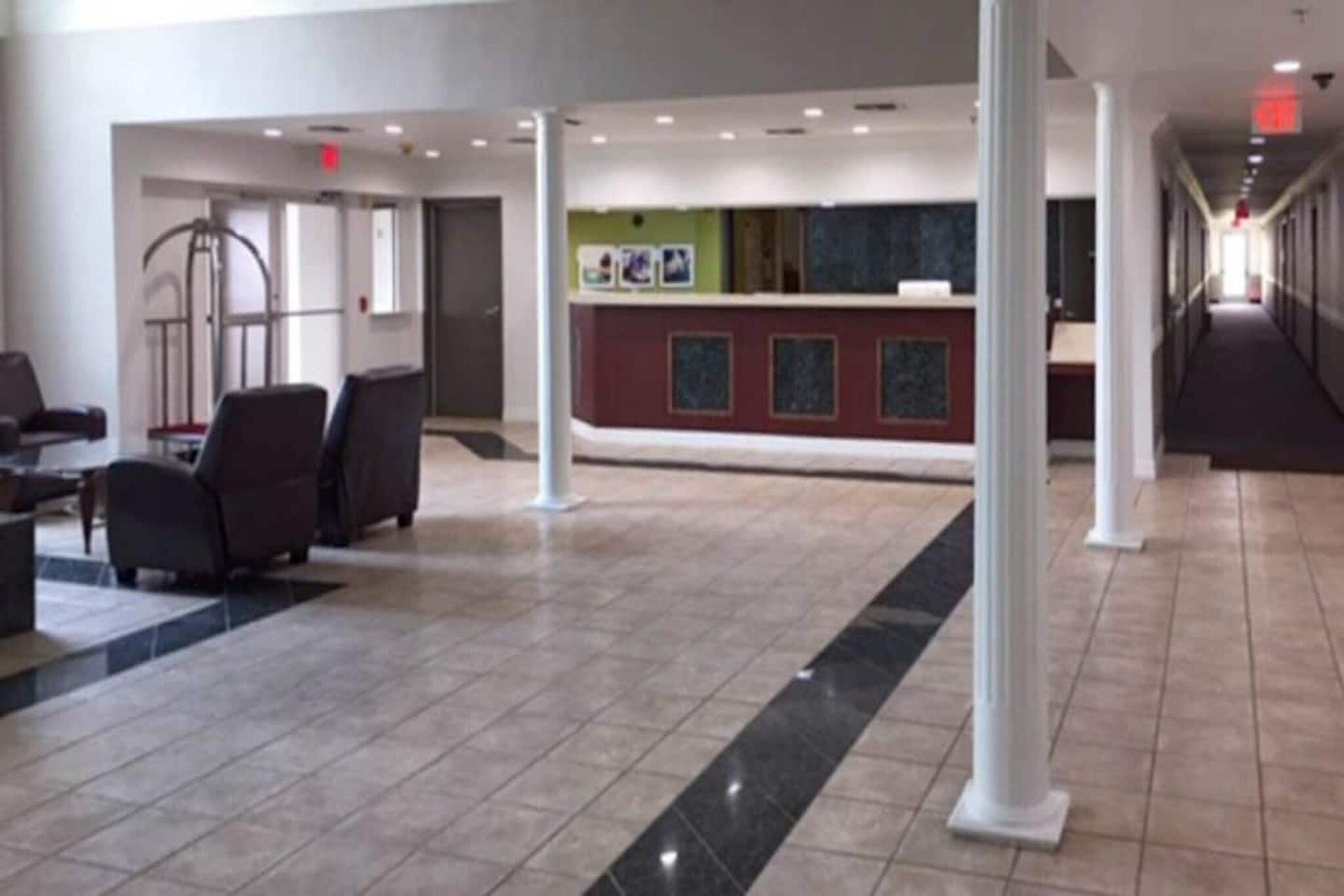 A spacious lobby with a reception desk, seating area, and a tiled floor.