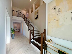 A staircase with wooden railings and a potted plant at the bottom landing. - Pickleball/Gameroom/Soccer Field/Pool (Miami)
