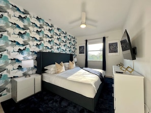 A modern hotel room with a bed, nightstands, a dresser, and a ceiling fan. - Pickleball/Gameroom/Soccer Field/Pool (Miami)