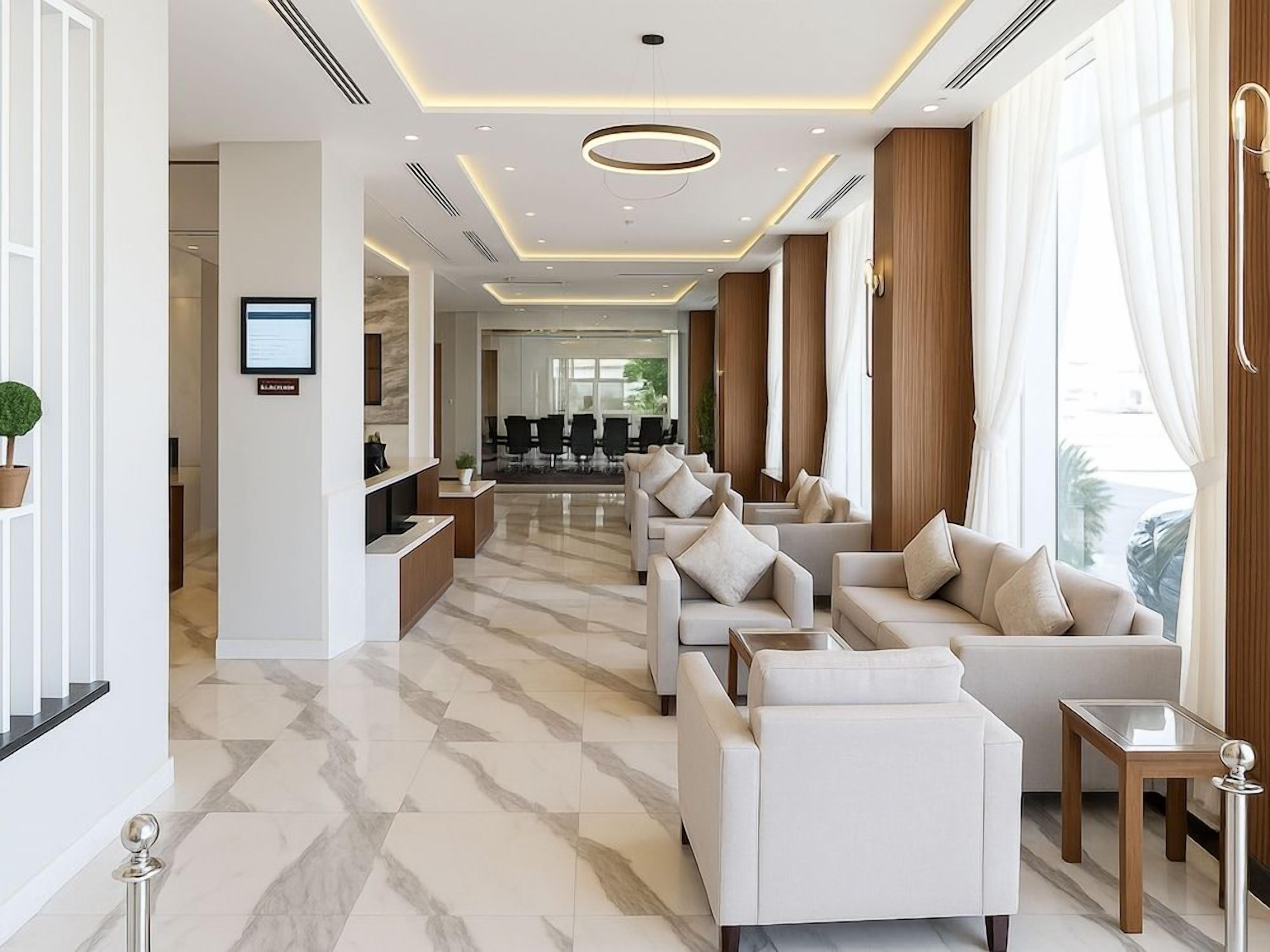 A modern hotel lobby with a reception desk, seating area, and a view of the dining area.