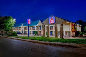 Un motel avec un panneau indiquant le chiffre « 6 », de nombreux balcons et un parking.