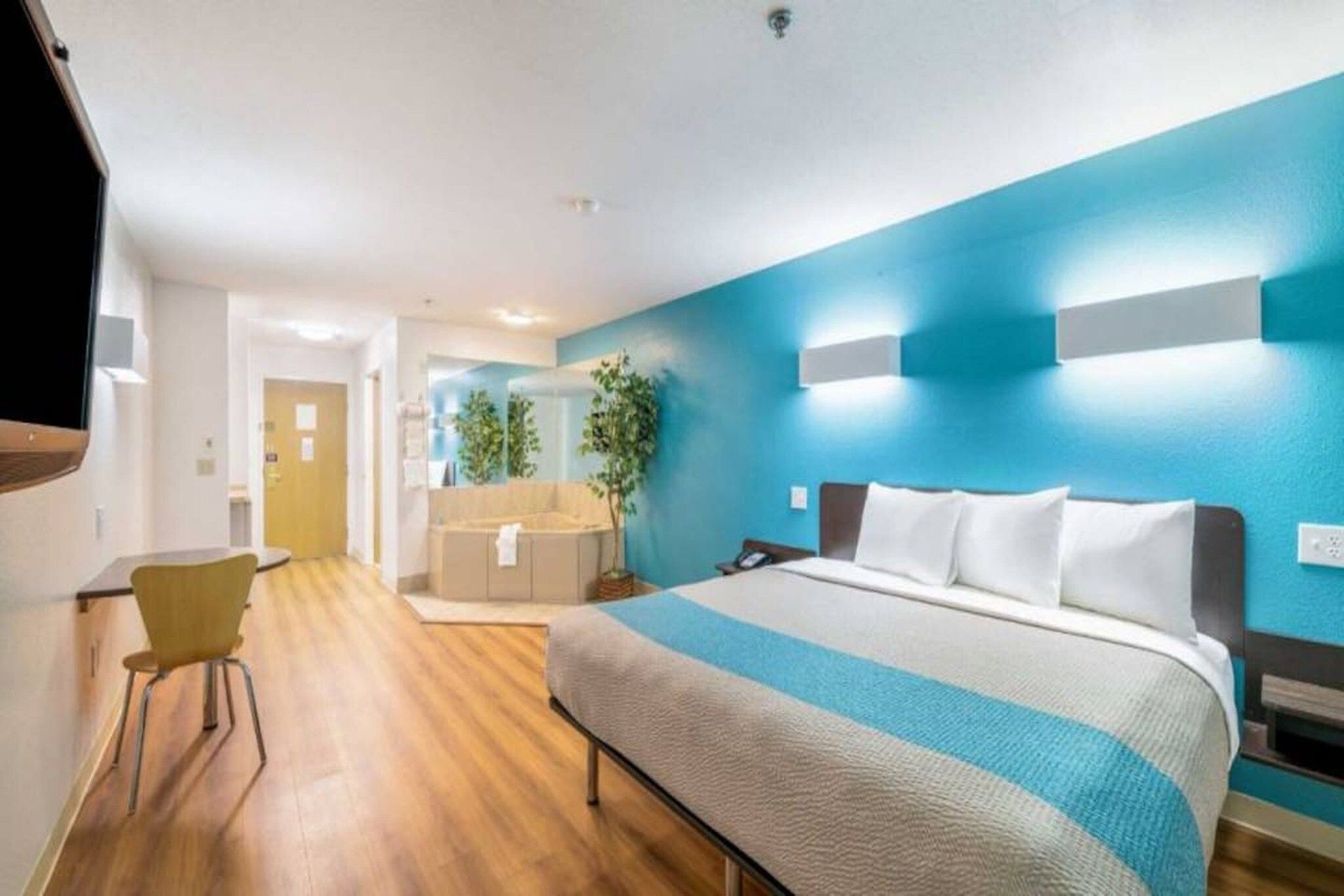 A hotel room with a bed, a desk, and a chair.