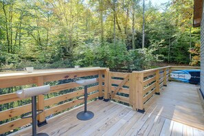 Une terrasse en bois avec une rambarde, un kayak et une forêt naturelle en arrière-plan.