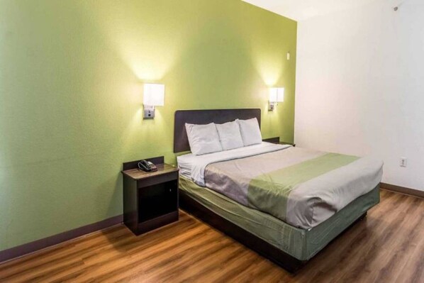 Una camera d'albergo con un letto, un comodino e un telefono.