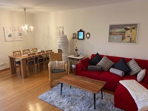 Ein Wohnzimmer mit einem roten Sofa, einem Holzesstisch und Stühlen.