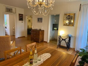 Ein Essbereich mit einem Holztisch, Stühlen, einer Chandelierleuchtre und einer Nähmaschine.