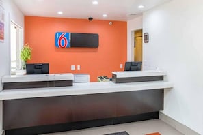 A reception desk with a digital display, two computer stations, and a plant. - Cozy 2 FULL BEDS | Nsmk (GRAND PRAIRIE)