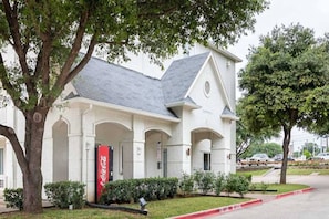 A building with a white facade, a grey roof, and a Coca-Cola sign. - Cozy 2 FULL BEDS | Nsmk (GRAND PRAIRIE)