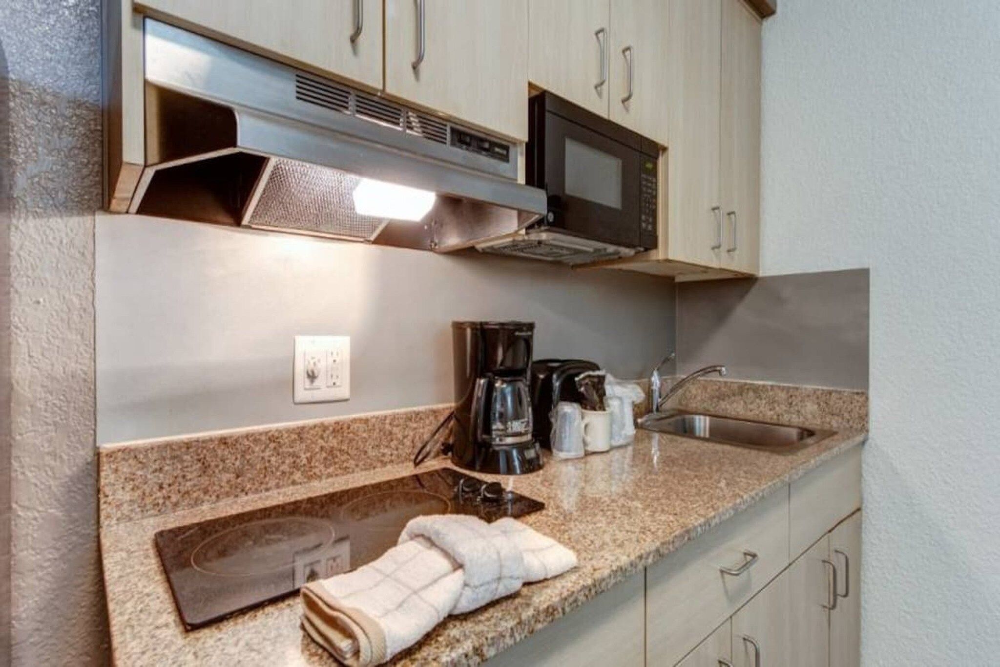 Una kitchenette equipada con microondas, cafetera y lavamanos.