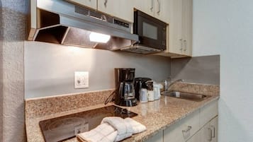 Una kitchenette equipada con microondas, cafetera y lavamanos.