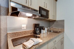 Een kitchenette met een magnetron, koffiezetapparaat en een spoelbak.