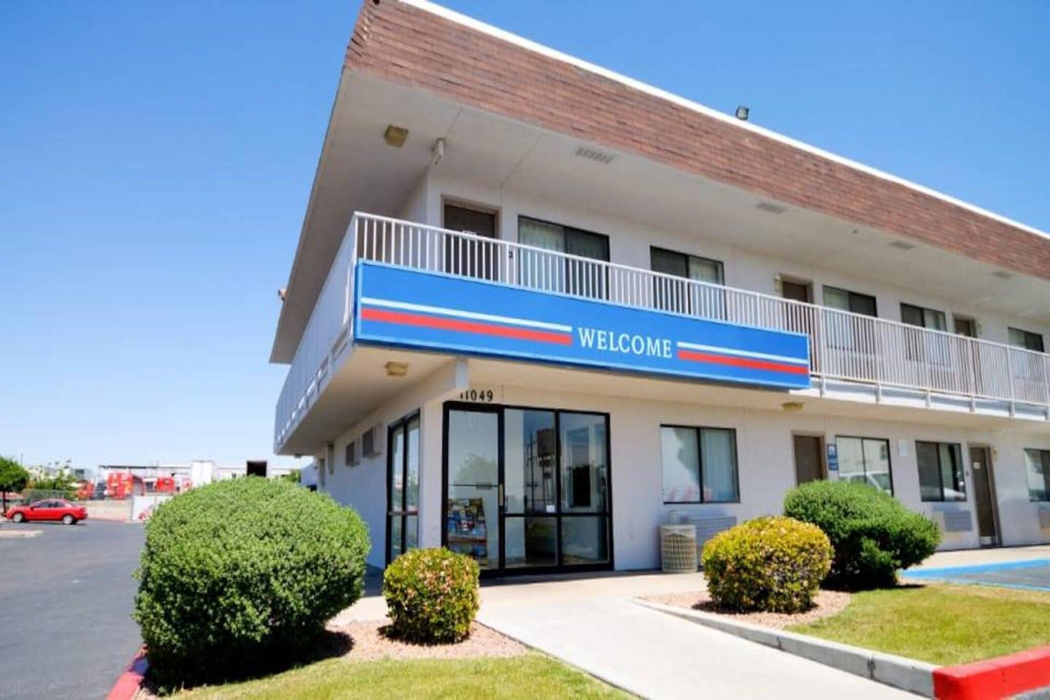 Un edificio con un letrero de 'BIENVENIDOS', un estacionamiento y jardines bien cuidados.