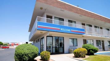 Un edificio con un letrero de 'BIENVENIDOS', un estacionamiento y jardines bien cuidados.