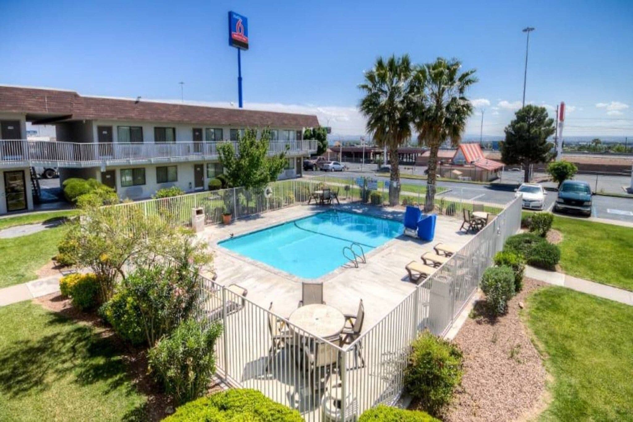 Un hotel con piscina, asientos exteriores y vistas del entorno.
