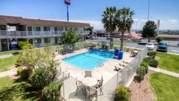 Un hotel con piscina, asientos exteriores y vistas del entorno.
