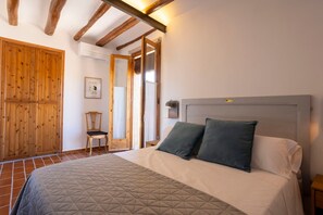 A bedroom with a bed, wooden wardrobe, and a chair.