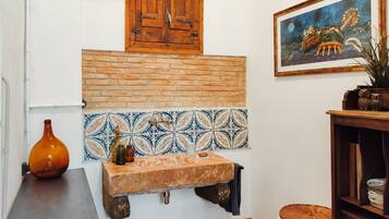 Cozinha com painel de azulejos, armário de madeira, pia e um quadro na parede.