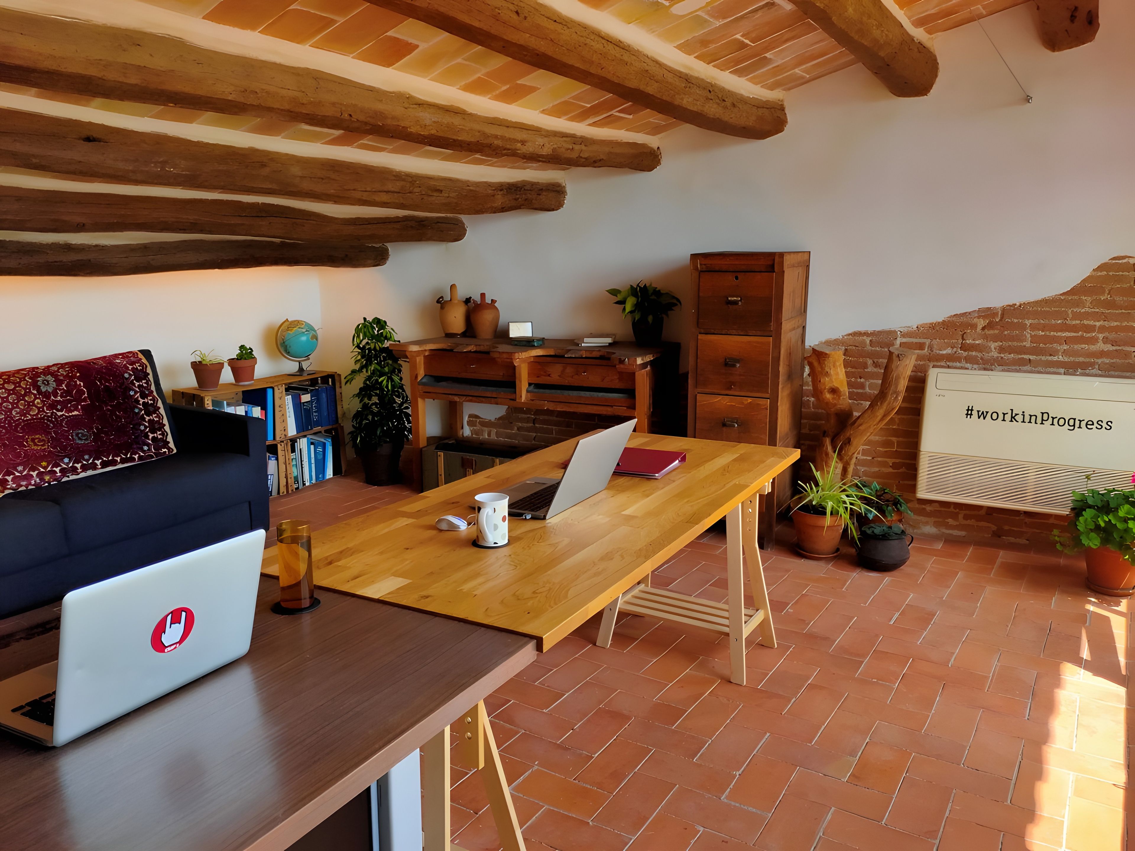 Un espace de travail confortable avec un ordinateur portable, un bureau en bois et un mur en briques.