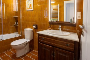 Un baño con inodoro, lavamanos, tocador y toallero.