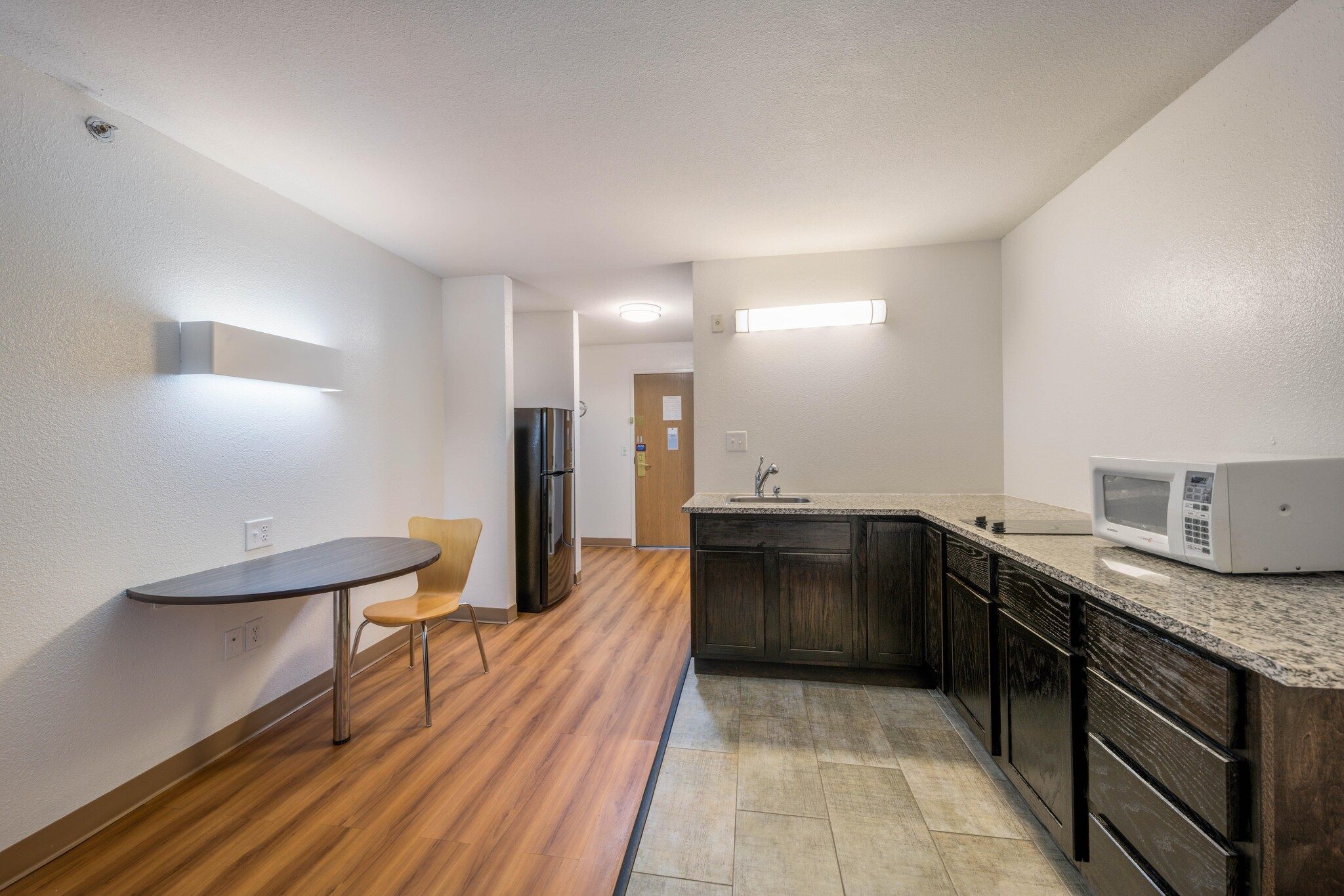 A compact kitchen with a dining table, a microwave, and a refrigerator.