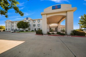 A hotel with a large entrance, multiple windows, and a parking lot. - 2 King Beds | Suite, Non-Smoking (Decatur TX)