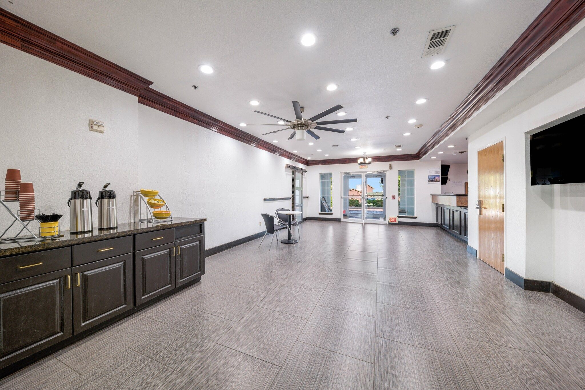 A spacious lobby with a ceiling fan, a reception desk, and a seating area.