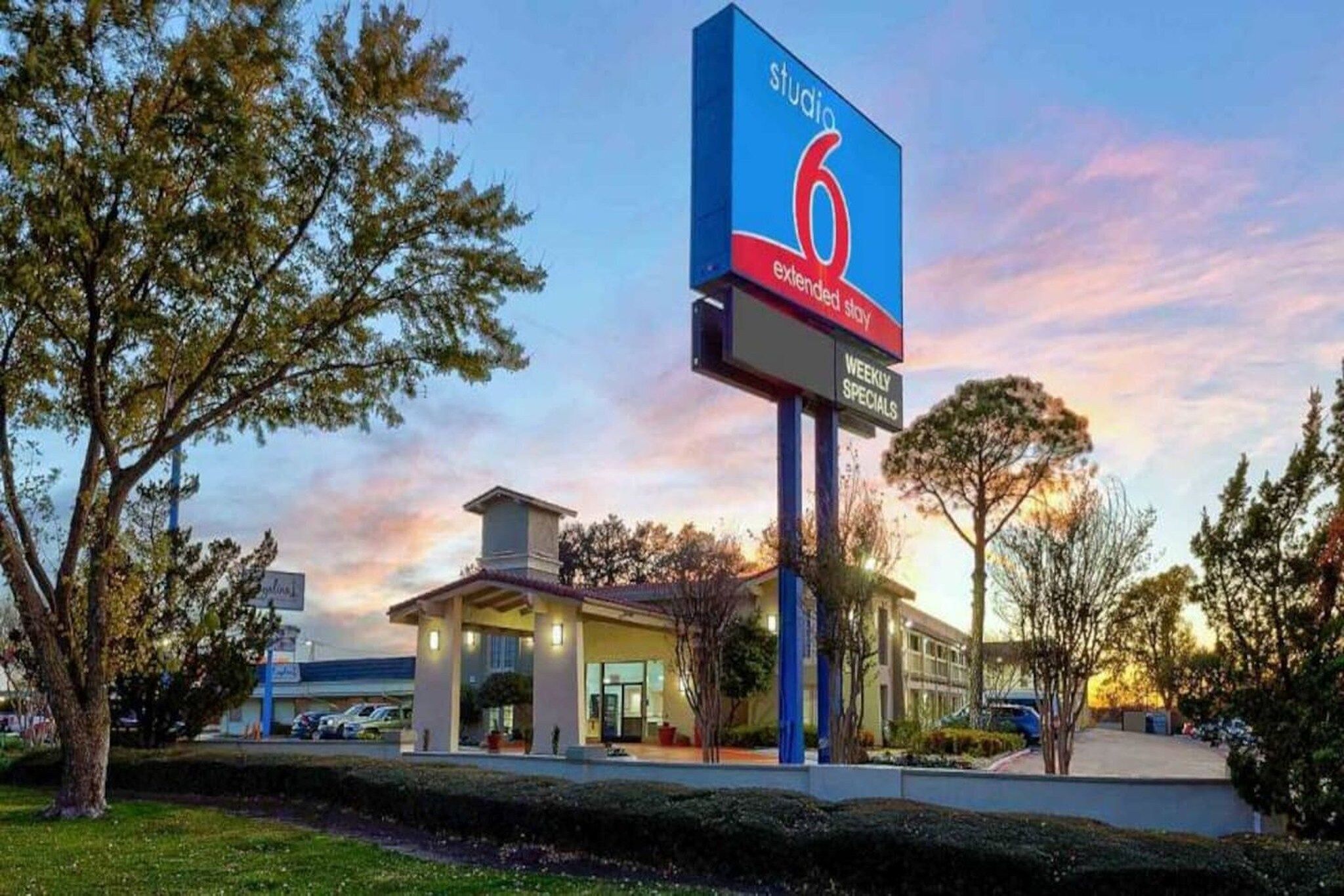 A hotel with a prominent sign indicating extended stay options and weekly specials.