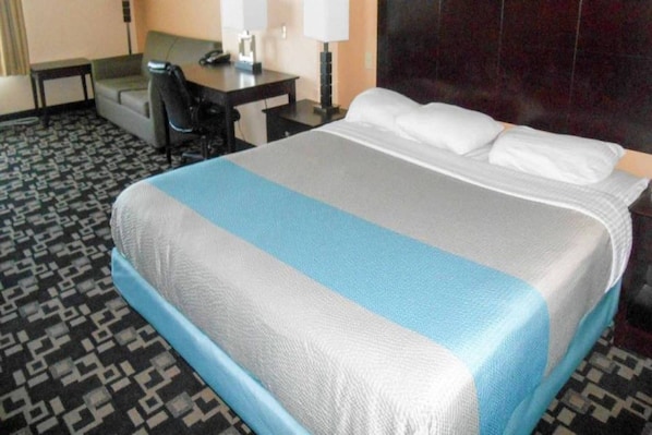 Una habitación de hotel con cama, escritorio, silla y lámpara.