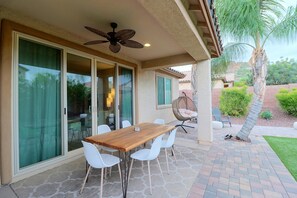A patio with a wooden table and white chairs, a ceiling fan, and a hanging chair. - Tucson Desert Escape Near Outdoor Adventures (Tucson)