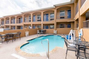 A hotel with a swimming pool, outdoor seating, and multiple balconies. - 2 Queen Beds | Smoking, Micfridge (ALVARADO)
