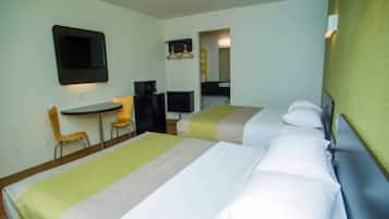 Ein Hotelzimmer mit zwei Betten, einem Schreibtisch, einem Sessel, einem Fernseher und einem durchgegangenen Badezimmer.