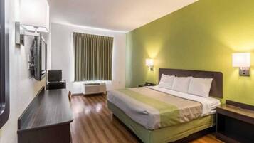 A hotel room with a bed, bedside table, lamp, and a window with curtains.