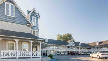 A motel with multiple-story buildings, a covered parking area, and a small garden.