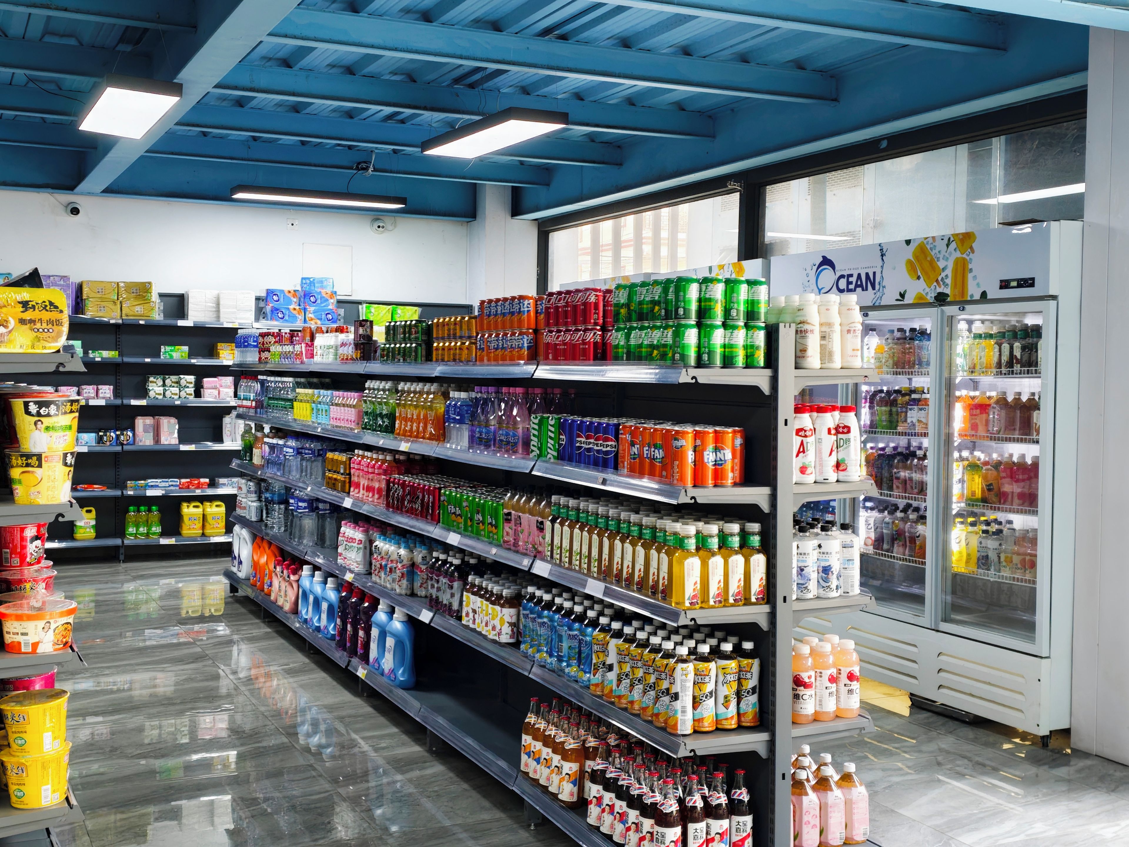 Un pasillo de supermercado con diversas bebidas y productos para el hogar.