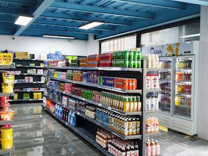Un pasillo de supermercado con diversas bebidas y productos para el hogar.