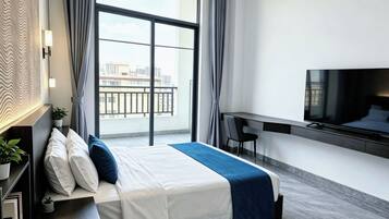 Una habitación de hotel moderna con cama, escritorio, televisión y vistas a la ciudad.