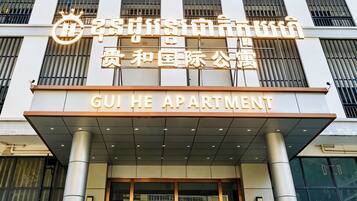 Un edificio con un cartel que dice 'GUI HE APARTMENT' y otro cartel con caracteres chinos.