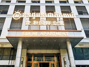 Un edificio con un cartel que dice 'GUI HE APARTMENT' y otro cartel con caracteres chinos.