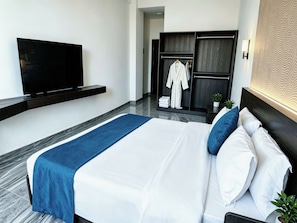 Una habitación de hotel con cama, televisión, armario y espejo.
