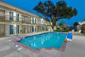 A swimming pool with a tiled deck, surrounded by a fence, and a large tree in the background. - 1 King Bed | Mobility Accessible Tub, Nsmk (DENTON)