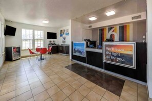 Un'area di accoglienza con un banco reception, sedie e un grande poster.