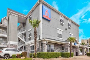 A multi-story hotel with a prominent '6 extended stay' sign, a covered outdoor area, and a parking lot. - 1 Queen Bed | Suite, Non-Smoking (Dallas)