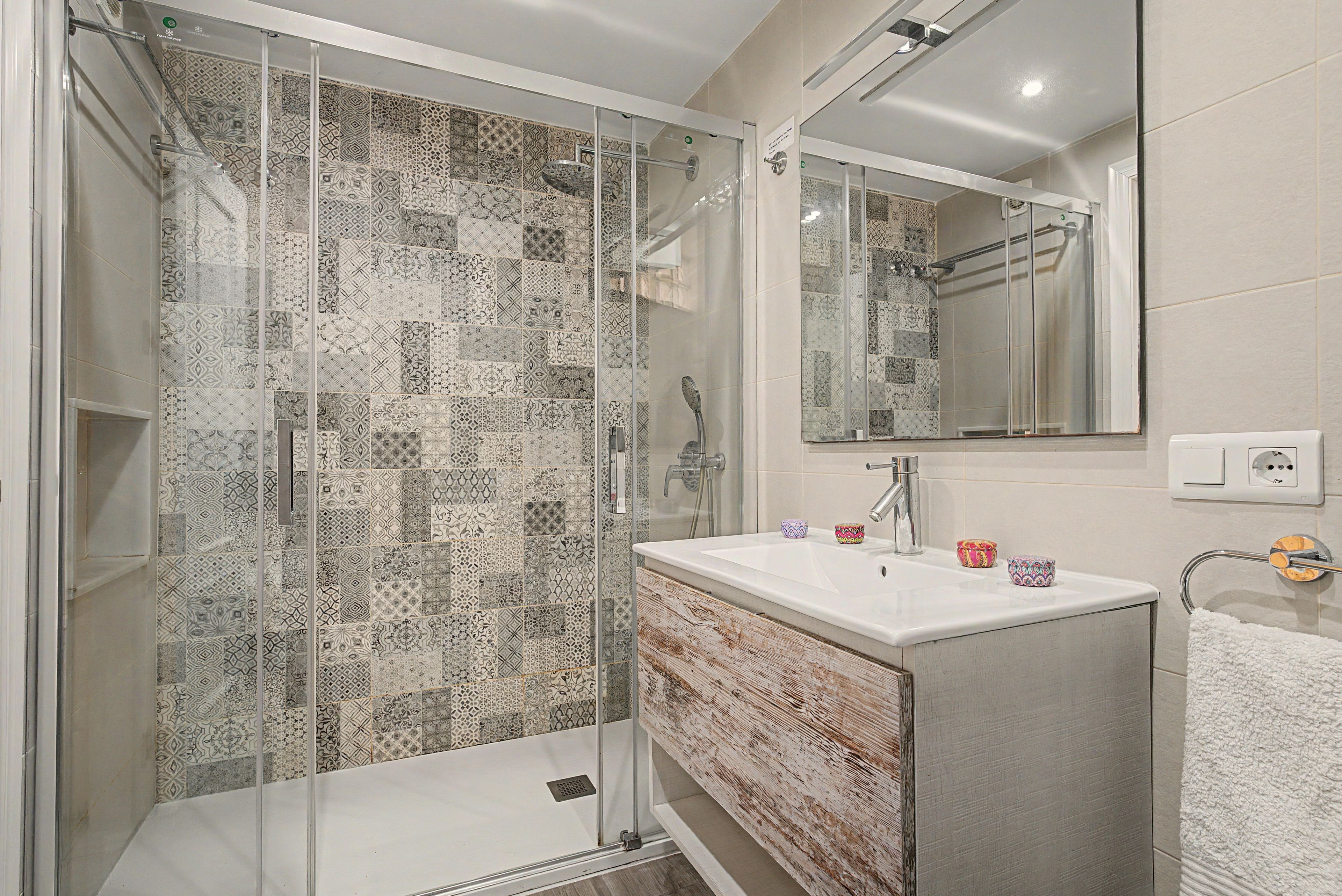 Une salle de bain moderne avec une douche à parois de verre, un lavabo blanc et un miroir au-dessus.